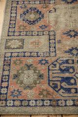 Close-up detail of distressed Anatolian rug runner, showing blush, cobalt blue geometric motifs with visible foundation.