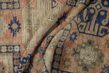 Folded vintage Anatolian runner shows starburst guls, blush, cobalt blue, and distressed texture.