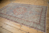 Distressed Sivas rug corner showing even wear, slate blue and brick red plant motifs.