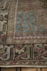 Distressed Oushak rug texture with worn olive green, dusty blue, and mauve patterns.