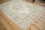 Distressed vintage Kayseri rug corner, showing softened ivory pile and scrolling pale pink arabesques.