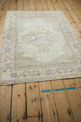 Vintage distressed Kayseri rug corner with soft, lustrous ivory and pale pink arabesque patterns.