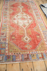 Distressed brick red field with ivory stepped medallion contour and blue, green borders on Oushak.