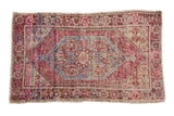 Distressed vintage Oushak rug, central floral bouquet in purple, blue, pink, ivory.