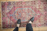 Top corner of distressed Oushak rug, showing worn purple, pink, and blue motifs.
