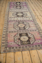Distressed Oushak runner's violet purple and beige medallion with geometric borders.