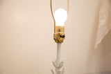 Illuminated bulb, brass socket, and white floral stem details.