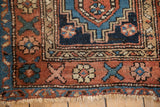 Detail of the coarse, hand-knotted pile and floral border on an antique Persian Heriz rug.