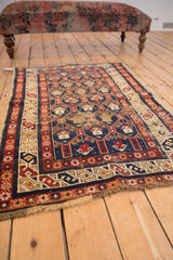 Antique Caucasian rug, geometric doubled boteh field, showing visible foundation and aged, tattered edges.