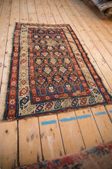 Worn central field of the antique Caucasian rug, displaying blue, red, and ivory geometric boteh motifs.