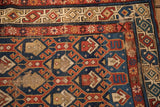 Antique Caucasian rug showing worn cobalt blue field, geometric botehs, and exposed foundation detail.