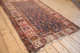 Antique Malayer rug corner, showing navy boteh field, geometric border, and worn fringe.