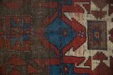 Close-up of hand-knotted Caucasian rug showing geometric motifs in sapphire blue, black cherry red, ivory.