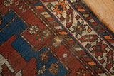 Geometric motifs and colors on vintage Caucasian rug showing visible holes and tattered edge.