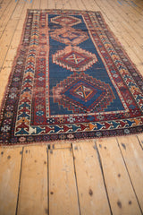 Antique Caucasian runner's geometric hook and latch medallions on a navy field with aged texture.