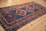 Antique Caucasian runner's geometric border in red, navy, and ivory showing storied wear.