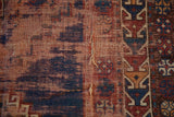 Antique Caucasian rug detail: threadbare pile, visible foundation, and a split with navy blue and aubergine patterns.