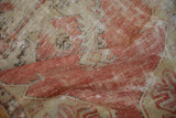 Distressed vintage Oushak rug fragment, showing worn pile, blush, beige, and exposed foundation.
