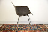 Side profile of elephant grey Eames fiberglass chair and gray base on blue floral Persian Hamadan rug.