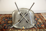 Underside of Eames elephant grey fiberglass chair, X-base, Zenith sticker on blue Hamadan rug.