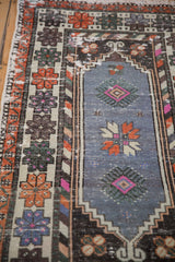 Distressed Oushak rug's geometric floral detail in faded blue, tangerine, and vibrant pink.