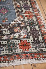Distressed Oushak runner's geometric tangerine florals, faded blue field, and hand-knotted fringe detail.
