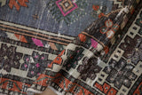 Folded vintage distressed Oushak rug runner showing geometric patterns in faded blue and tangerine.