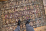 Distressed vintage Melas rug, showing geometric patterns, visible wear in beige and blush.