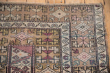 Distressed Melas rug corner showing geometric patterns, vine border, and visible foundation wear.
