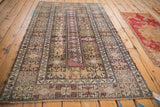 Distressed Melas rug corner, geometric plants, pale blush vine border, and visible wear.