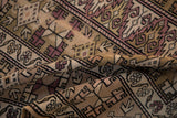 Folded vintage distressed Melas rug with worn geometric germinating plants in beige and pale blush.
