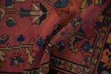 Folded antique Lilihan rug pile with primitive dusty raspberry and navy floral motifs.
