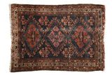 Antique Persian Mehriban rug, triple medallions on dark navy, rust, fuchsia, and visible wear.