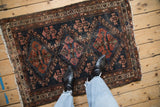 Antique Mehriban rug displaying worn dark navy field with copper and raspberry triple medallions.