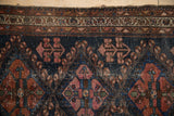 Worn dark navy field of antique Mehriban rug with faded raspberry plants and vine border.