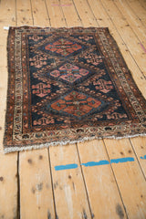 Worn corner of antique Persian Mehriban rug, dark navy field, plant motifs, foundation visible.