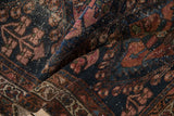 Textured detail of an antique Persian Mehriban rug with navy field, copper motifs, and foundation wear.