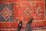 Textured distressed vintage Kurd runner showing burnt orange and aubergine checkered diamond motifs.