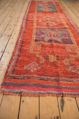 Vintage Kurd rug runner showing distressed orange pile texture, geometric motifs, and aubergine border fringe.