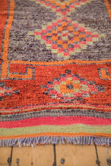 Distressed vintage Kurd runner, showcasing worn fringe and vibrant geometric orange, aubergine pattern.