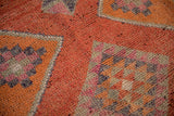 Distressed vintage Kurd rug texture showing coral, orange, magenta abrashes and serrated motifs.