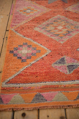 Distressed Kurd runner pile showcasing geometric pinwheel floral motifs in vibrant orange and coral.