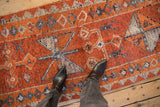 Distressed Kurd rug runner with playful geometric patterns in burnt orange, ivory, and silver.