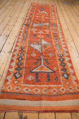 Textured pile of a distressed Kurd runner with burnt orange and ivory patterns.