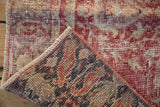 Distressed vintage Sparta rug showing faded raspberry pile, wear, and its distinct patterned reverse.