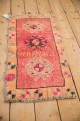 Detail of a vintage distressed Kars rug showing a central medallion, inscribed weaver name, and fuchsia accents.