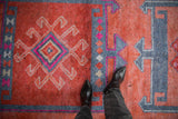 Distressed Kurd runner pile showing faded ruby red, blue, and fuchsia geometric patterns.