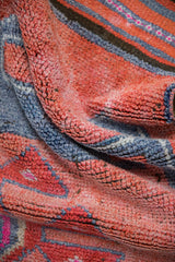Textured, distressed pile detail of a Kurd runner in faded ruby red and blue.