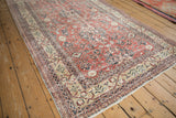 Distressed brick red Sparta carpet with visible wear and an antique ivory vine border.