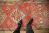 Distressed vintage Kurd runner, showing geometric medallions and short pile texture in orange hues.